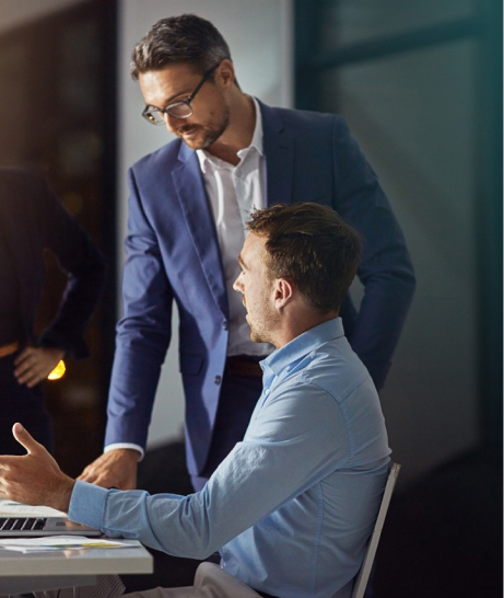 Deux hommes discutent sur un sujet de travail à côté d’un ordinateur. 