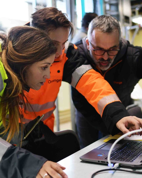 Trois membres d’Orange étudient et commentent un document sur un ordinateur 