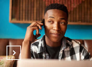 Un jeune africain travaille sur son ordinateur pendant qu’il est au téléphone