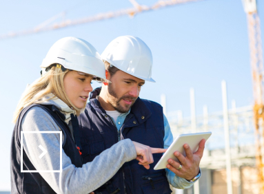 Deux personnes sur un chantier regardent une tablette numérique de travail.