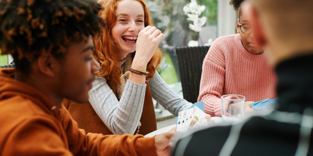 Quatre élèves s’amusent et jouent aux cartes autour d’une table.